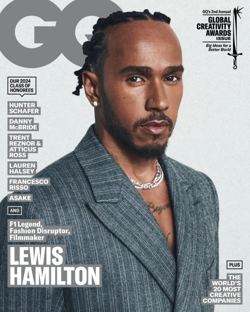 Lewis Hamilton on the cover of GQ magazine, posing in a grey pinstripe suit with a serious facial expression and multicolored necklace.