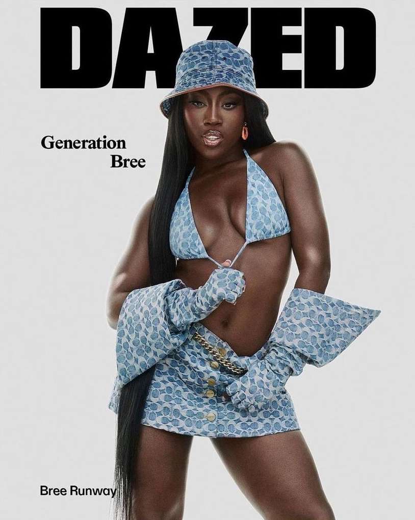 An adult woman in a denim-patterned two-piece outfit and bucket hat poses for a magazine cover against a white background.