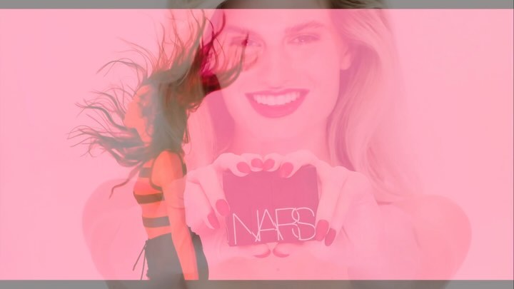 Smiling woman with long blonde hair poses indoors, holding NARS makeup in front of a pink background with a blurred dancer.