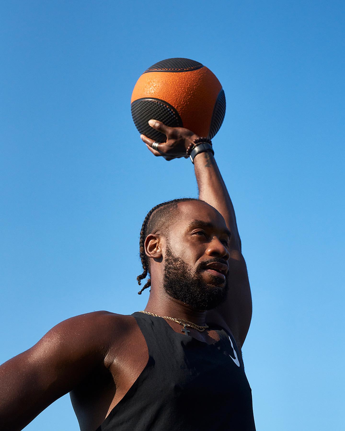 Athletic Black man working out outdoors with a medicine ball against a clear blue sky. Fitness and exercise concept.