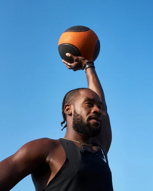 Athletic Black man working out outdoors with a medicine ball against a clear blue sky. Fitness and exercise concept. 