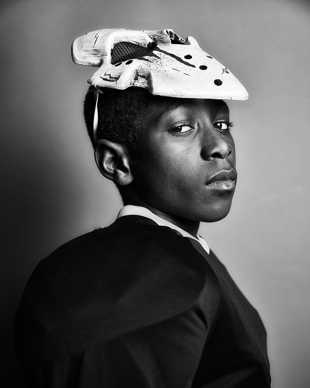 Portrait of African American male with hockey mask on head in black and white. Studio shot of person wearing sport equipment.