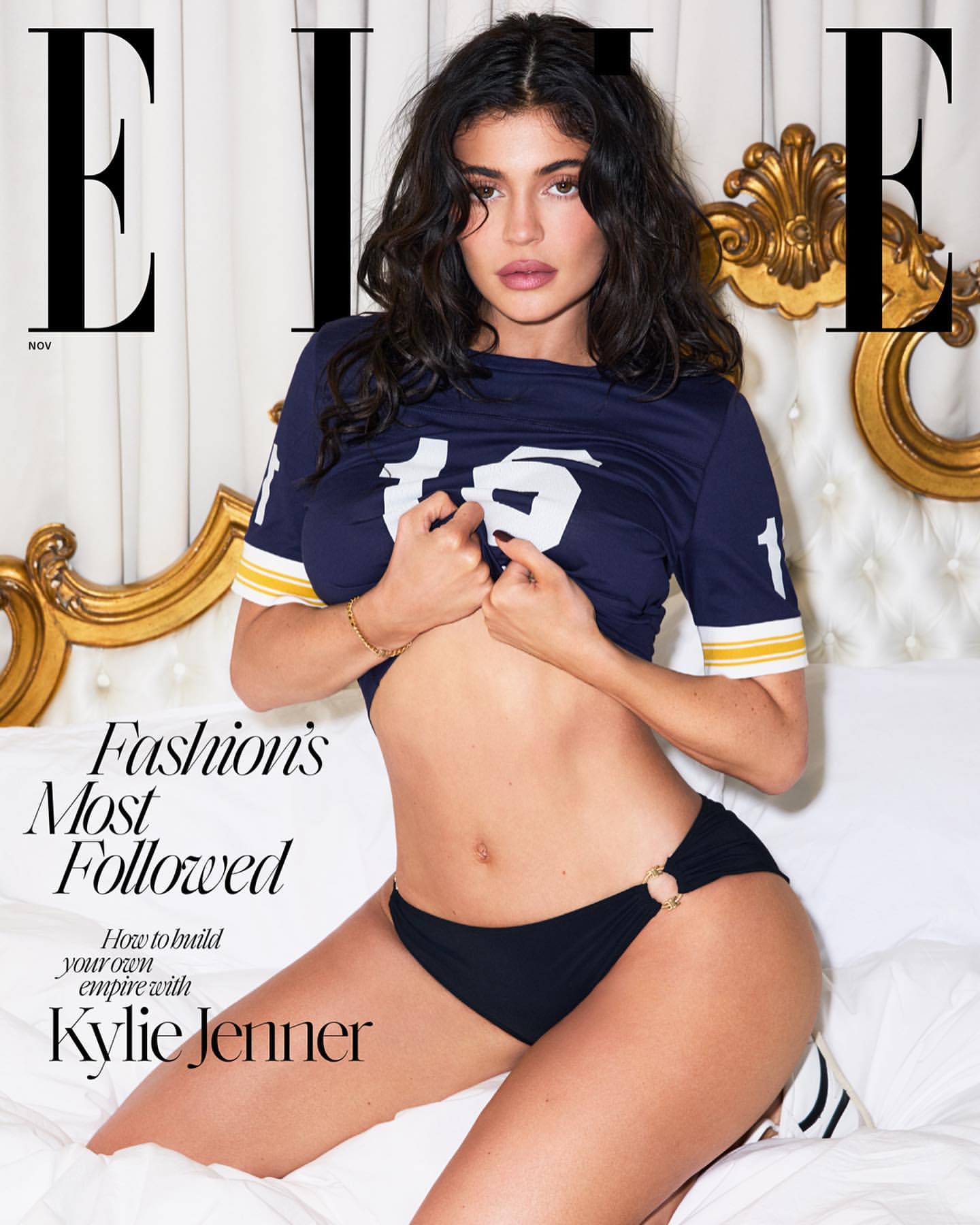 Elle cover featuring Kylie Jenner in a sporty top and black bikini bottom posing on a white bed with a gold headboard.