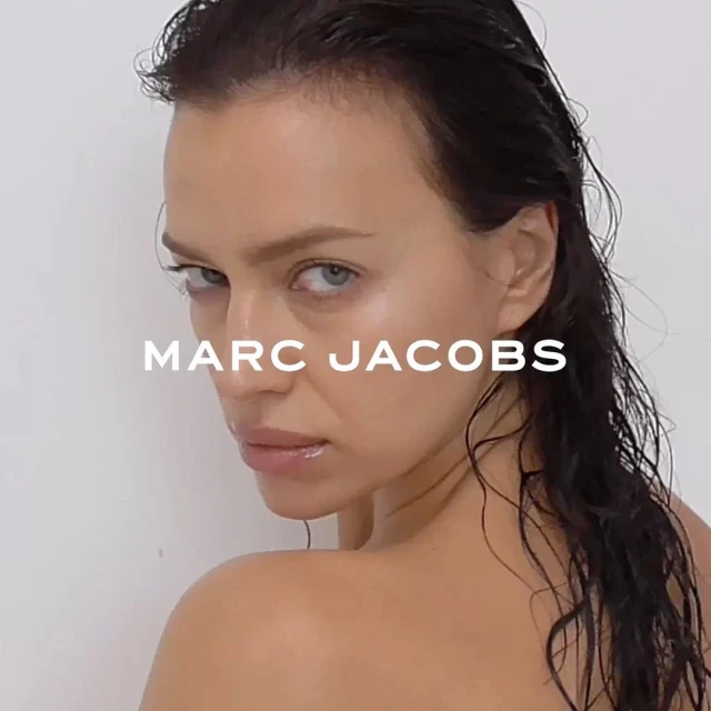 Close-up portrait of a female adult with wet dark hair, looking over shoulder, featuring visible skin tones and a clean white background.