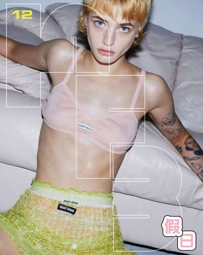 Close-up portrait of a blonde woman wearing a pink bralette and textured lime green skirt against a white leather sofa.