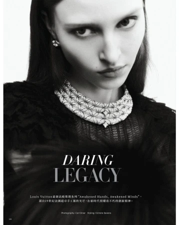 Monochrome portrait of a woman with long dark hair wearing an ornate diamond necklace and earring, set against a blurred background.