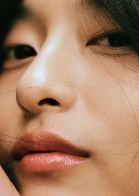 Close-up portrait of an Asian woman's face featuring dark hair, almond-shaped eyes, nose, and glossy lips, showcasing beauty and fashion.