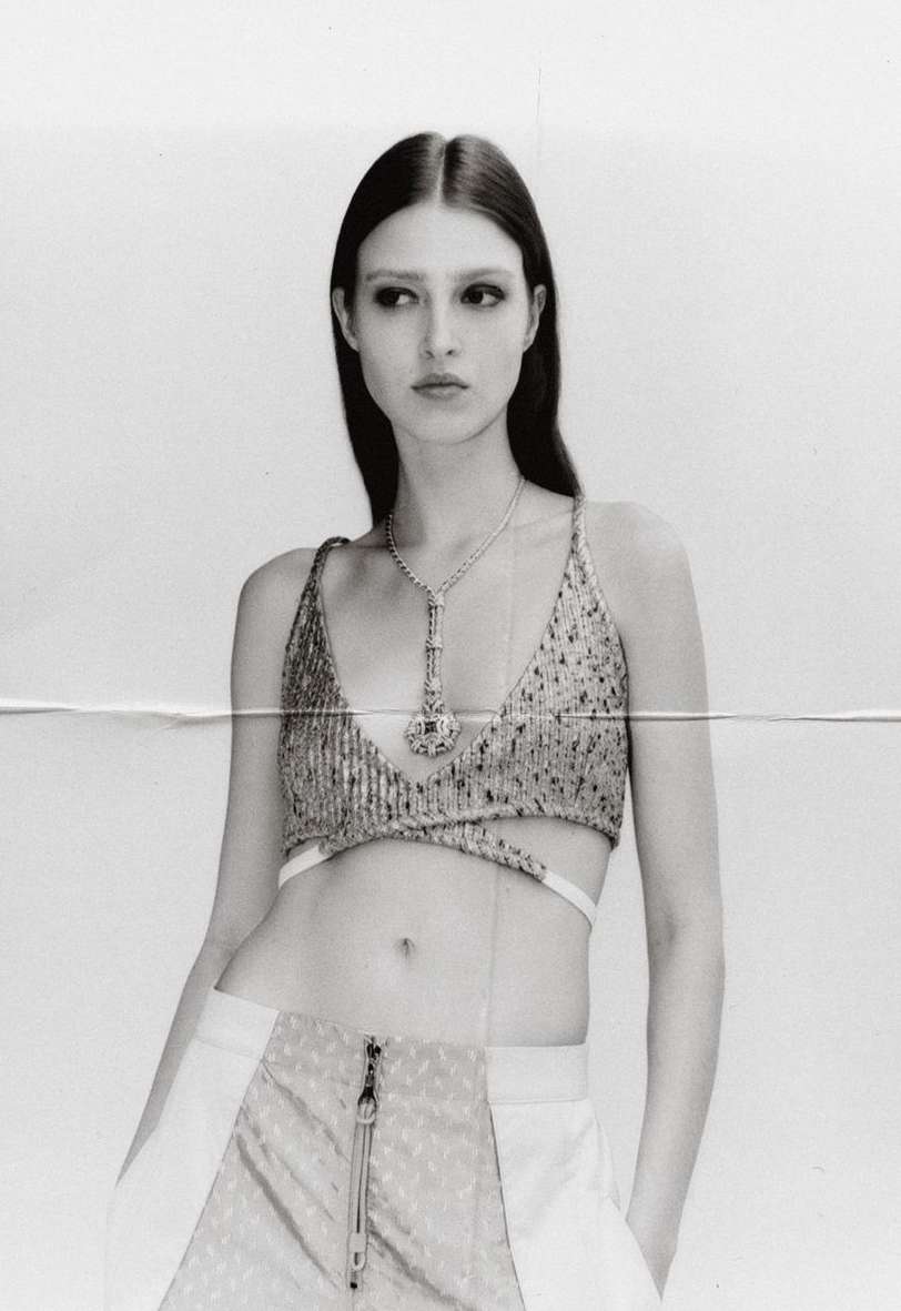 Monochrome portrait of a model wearing a sequin top and pants, gazing away from the camera in a photo studio setting.