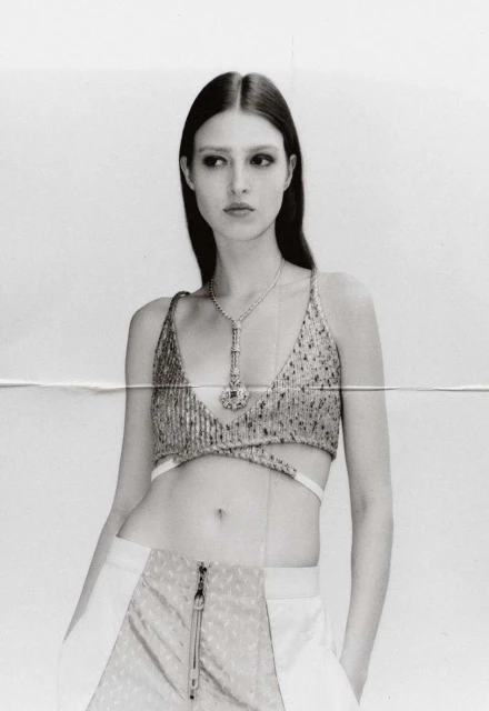 Monochrome portrait of a model wearing a sequin top and pants, gazing away from the camera in a photo studio setting.
