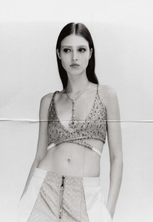 Monochrome portrait of a model wearing a sequin top and pants, gazing away from the camera in a photo studio setting.