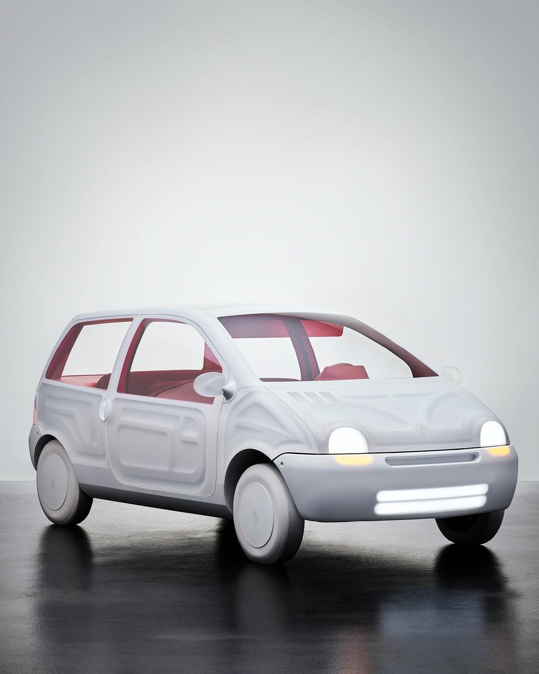 Studio shot of a white compact car with red interior details, headlights illuminated, against a gradient gray background.