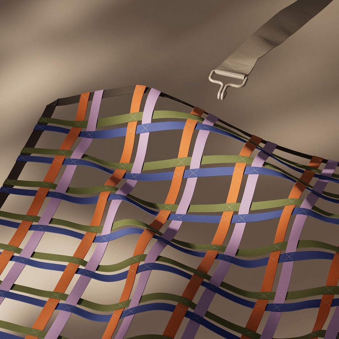 Woven pattern of orange, green, blue, and purple ribbons creating a net or grid, attached with a webbing strap and metal buckle.