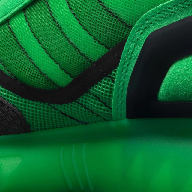 Close-up on a green and black athletic shoe featuring a breathable mesh upper, structured overlays, and a responsive sole for sports.