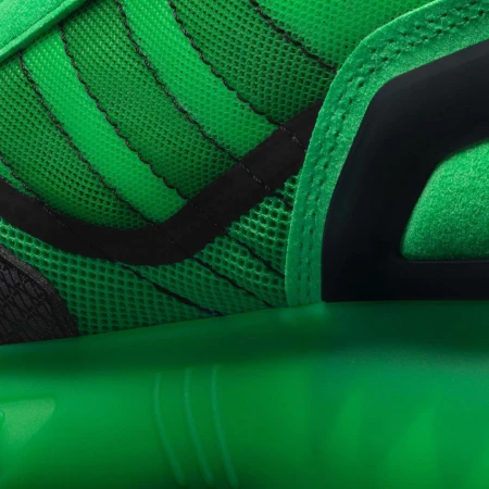 Close-up on a green and black athletic shoe featuring a breathable mesh upper, structured overlays, and a responsive sole for sports.