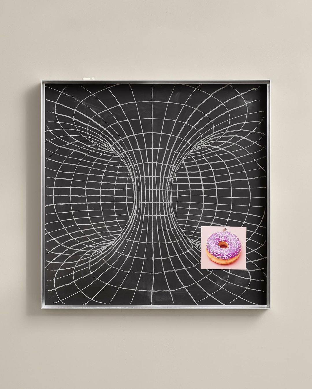 Abstract illustration of a black chalkboard with a wormhole graphic and a donut on pink paper attached, conveying a mix of science and snack.