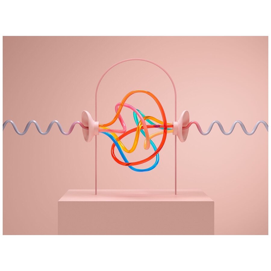Abstract art: pink stand supporting a framework holding rainbow-colored tubes against a soft pink background, creating a modern, minimalist aesthetic.