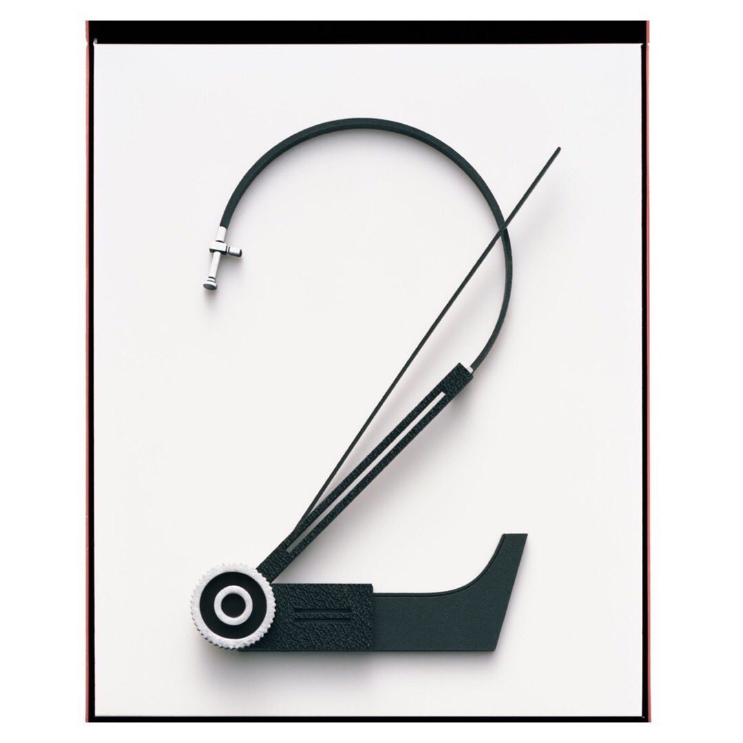 Abstract clock hand art. The clock hand is bent to make the shape of a number two set against a bright white background. 