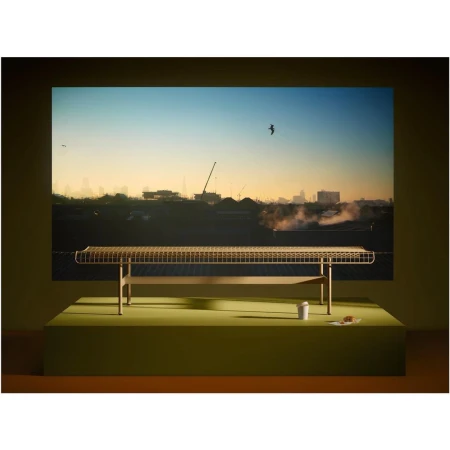 Woven bench on a lime green platform in a studio, displayed against an image of a cityscape during sunrise.