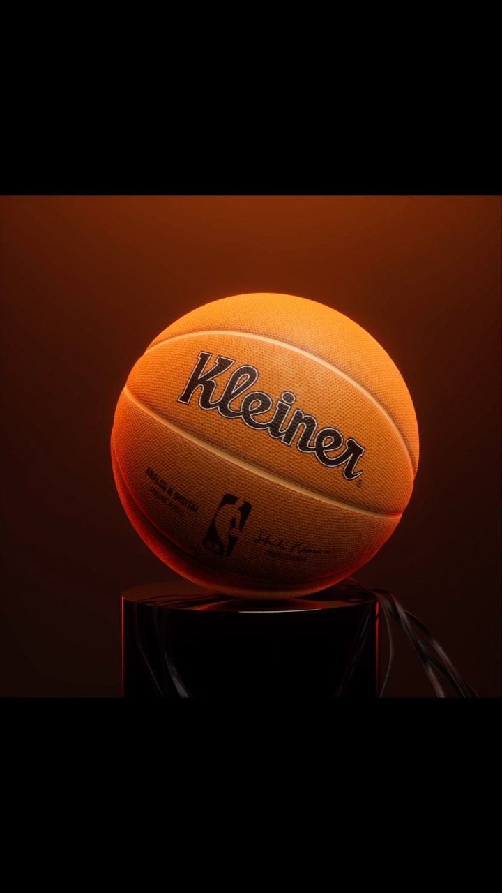 Close-up of an orange basketball with 'Kleiner' printed on the side, resting on a black pedestal against a dark gradient background.