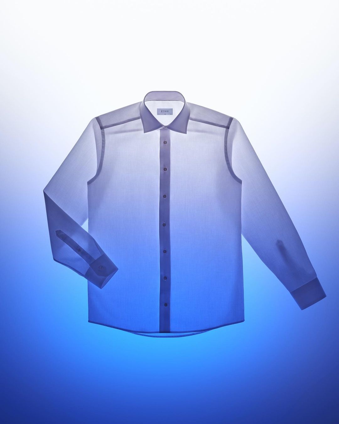 Studio shot of a light blue and white long-sleeved, button-down dress shirt, emphasizing its design and color against a graduated background.
