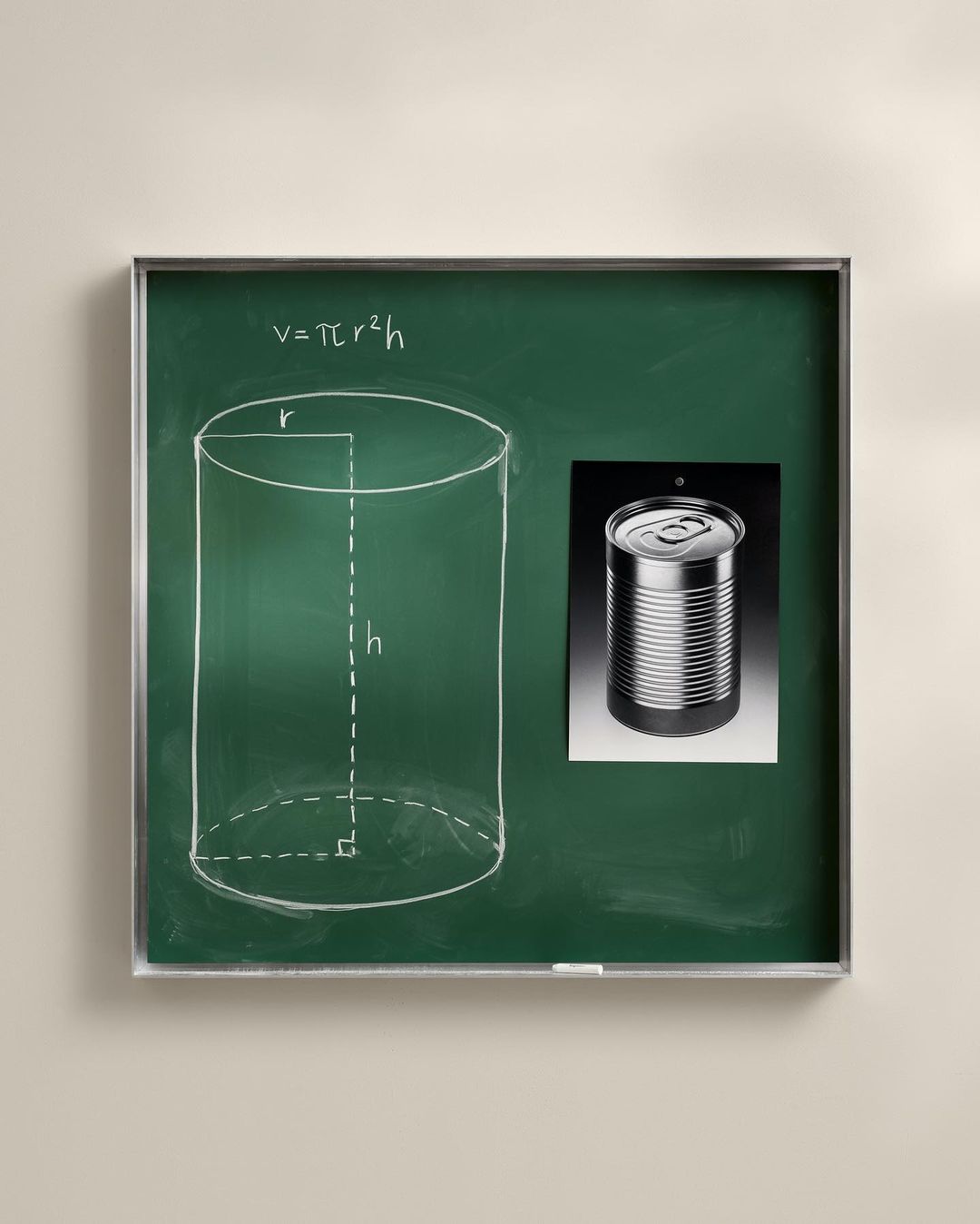 Chalkboard displaying a diagram of a cylinder and its volume formula with a photo of a can attached to the board.
