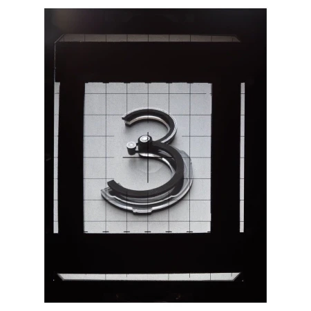 Abstract shot of the number three centered, made of layered grey material, surrounded by dark-grey square frame and a light-grey grid