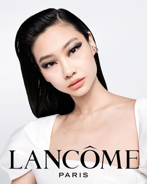 Close-up of an adult woman with dark hair and smokey eyes, modeling for a Lancôme beauty advertisement in a photo studio.