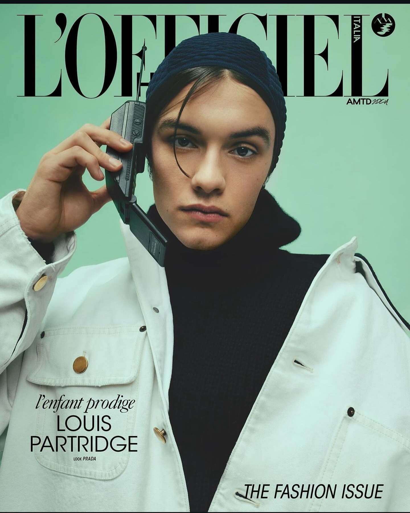 Magazine cover featuring Louis Partridge with a retro mobile phone, wearing a beanie and white jacket against a mint-green background.