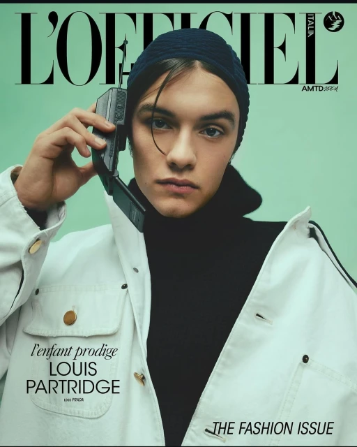 Magazine cover featuring Louis Partridge with a retro mobile phone, wearing a beanie and white jacket against a mint-green background.