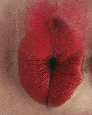 Close-up macro shot of bright red lipstick applied to parted lips with visible texture.