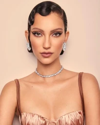 Close-up portrait of a woman with finger waves hairstyle, winged eyeliner, diamond choker necklace, and sparkling earrings.