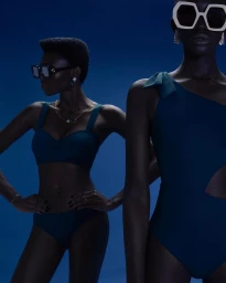 Two black women wearing dark swimwear and statement sunglasses against a deep blue background in a fashion portrait by Carla Guler.