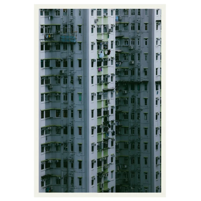Dense urban apartment blocks tower with rows of windows and air conditioning units, emphasizing the high-density architecture of city living.