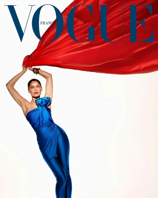Fashion editorial featuring a model in a blue dress holding a red fabric against a white backdrop for a Vogue France magazine cover.