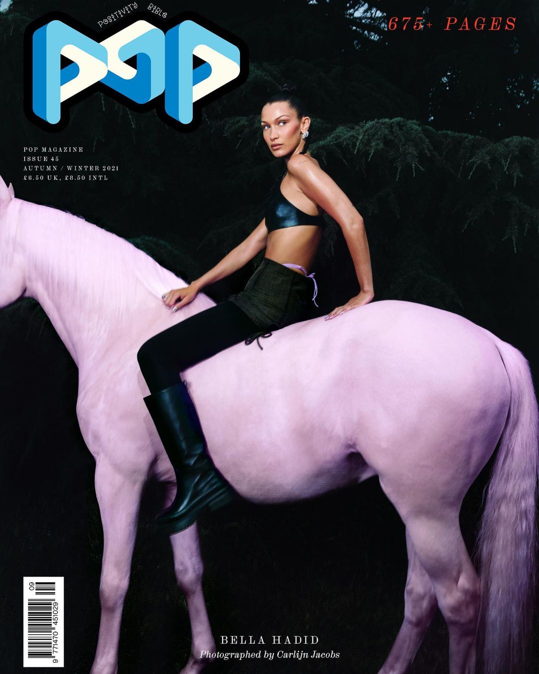 Bella Hadid poses on a pink horse for a magazine cover, set against a dark forest background, creating a striking, surreal fashion image.
