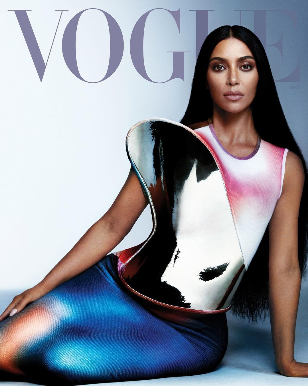Celebrity Kim Kardashian poses in a futuristic dress on the cover of Vogue, showcasing beauty and high fashion in a studio setting.