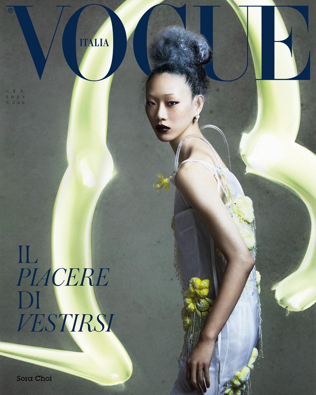 Vogue Italia cover featuring an Asian woman with an elaborate updo, wearing a sheer dress with floral appliqués and dark lipstick.