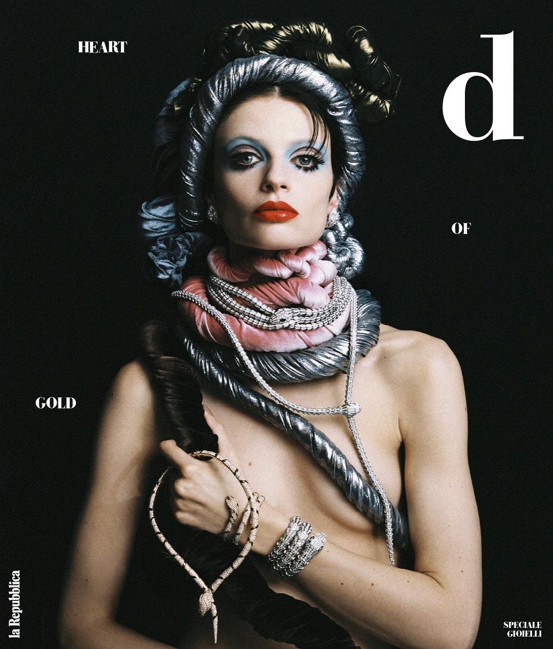 Fashion editorial portrait of an adult woman wearing makeup and jewelry with a black background for a magazine cover.