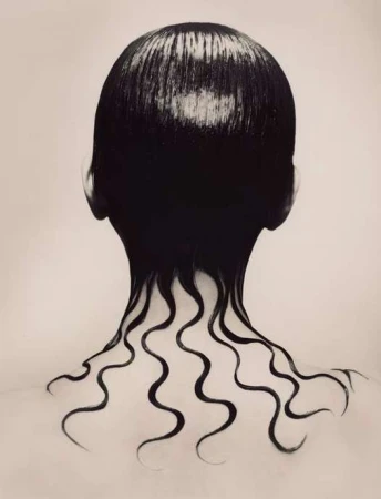 Rear view of a person with slicked wet black hair cascading in wavy tendrils down the neck and bare shoulders.