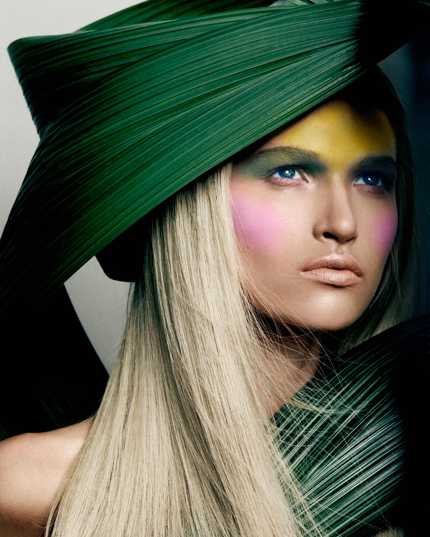 A woman with a leaf hat and creative makeup poses in a beauty or fashion shot with soft lighting, enhancing the natural textures and tones.