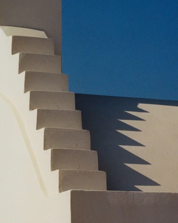 Minimalist architectural shot of concrete stairs ascending against a solid blue sky by photographer Carlo Piro