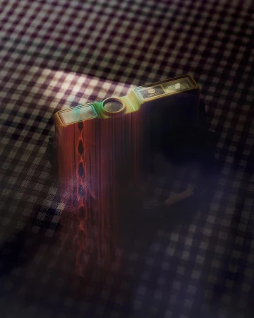 Vintage gold and green film camera resting on a checkered tablecloth in a dimly lit setting, creating a nostalgic and moody scene.