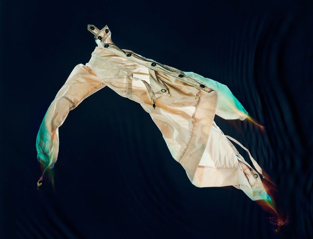 Floating beige jacket with colorful light trails against a dark textured background photographed by Carlo Van De Roer