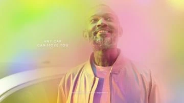 An adult man with a gray beard looking up, wearing a light-colored jacket, against a blurred multicolored background with text.