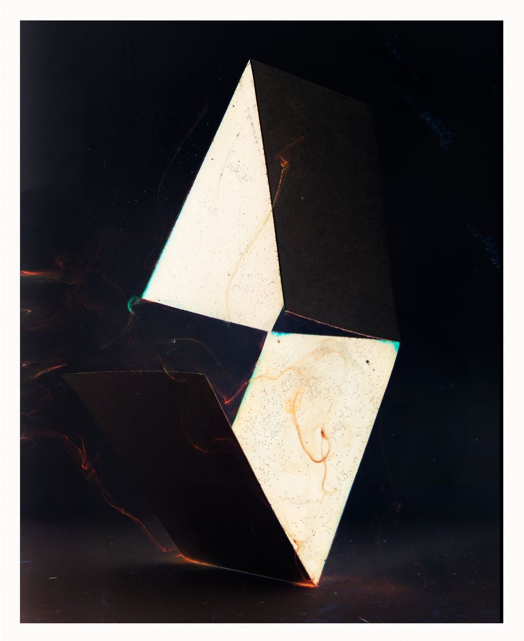 Abstract geometric sculpture featuring light and shadow contrasts against a dark background, creating a visually striking composition.