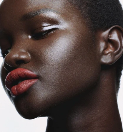 Close-up beauty portrait of a Black woman with glossy skin and bold red lipstick against a clean white background