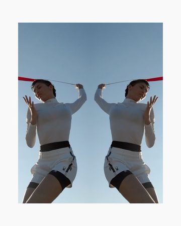 Digitally duplicated image of a person in sportswear holding a red ribbon against a blue sky backdrop, creating a mirrored symmetrical effect.