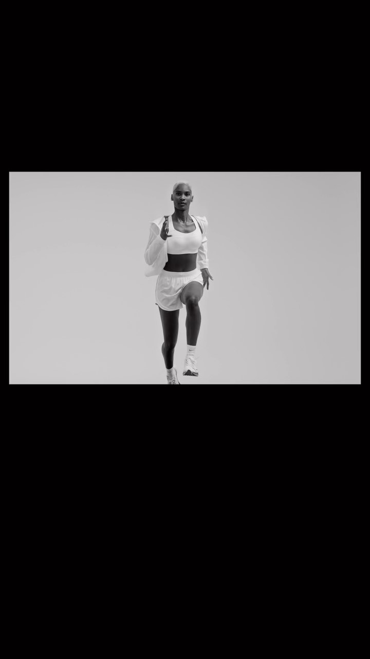 Athletic woman in white workout clothes running indoors against a neutral background in a fitness or sports context.