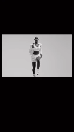 Athletic woman in white workout clothes running indoors against a neutral background in a fitness or sports context.
