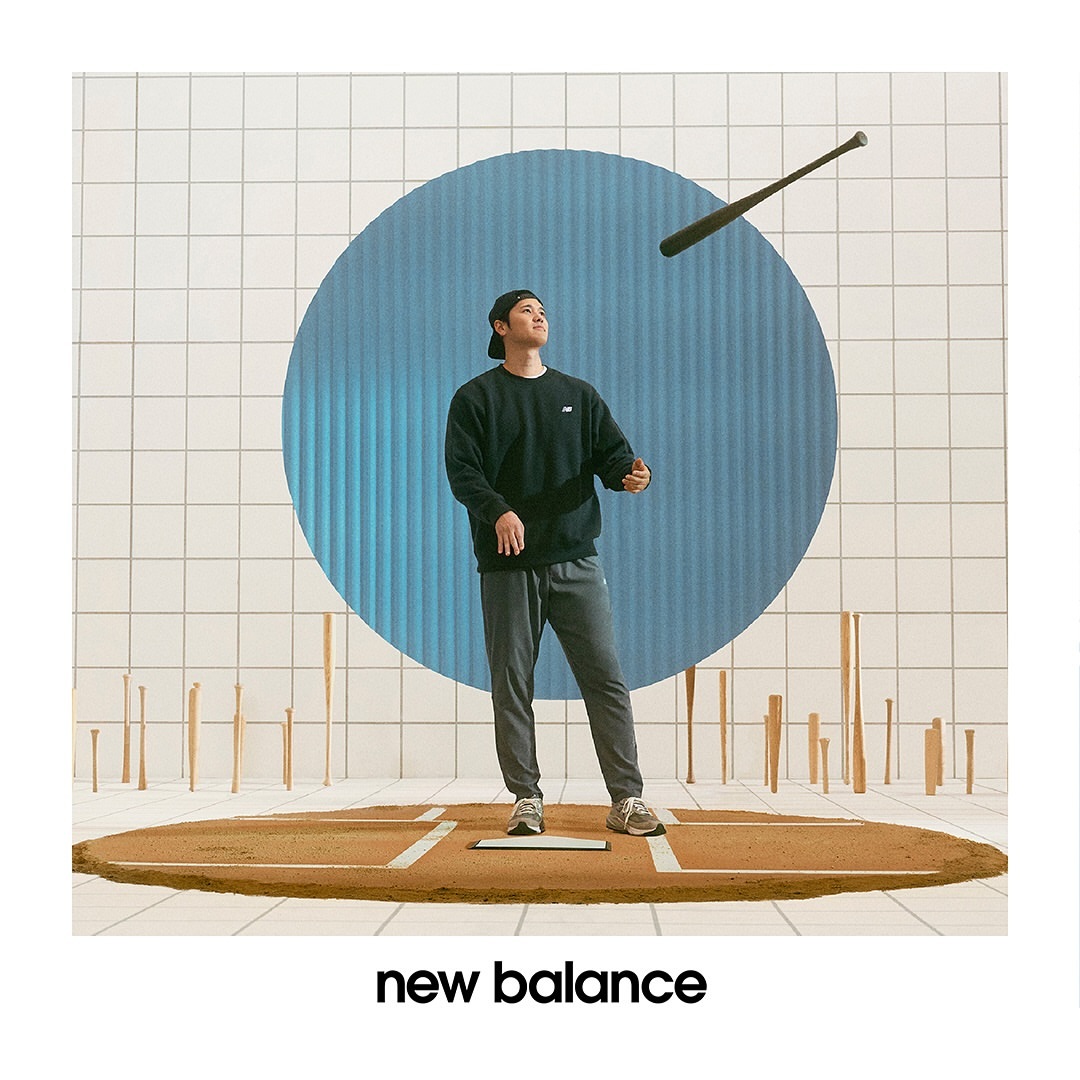 An Asian man in casual clothing stands on a baseball diamond with a floating bat, set against a graphic tiled backdrop and circle.
